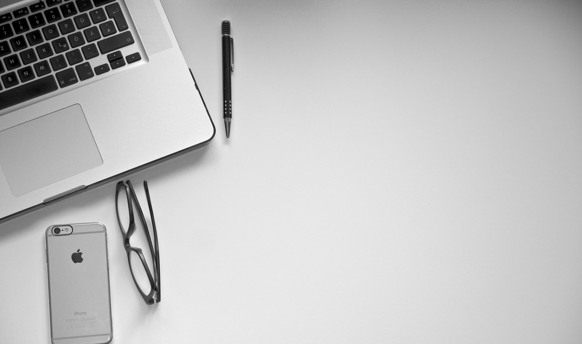 a laptop, a pair of glasses, a phone and a pen